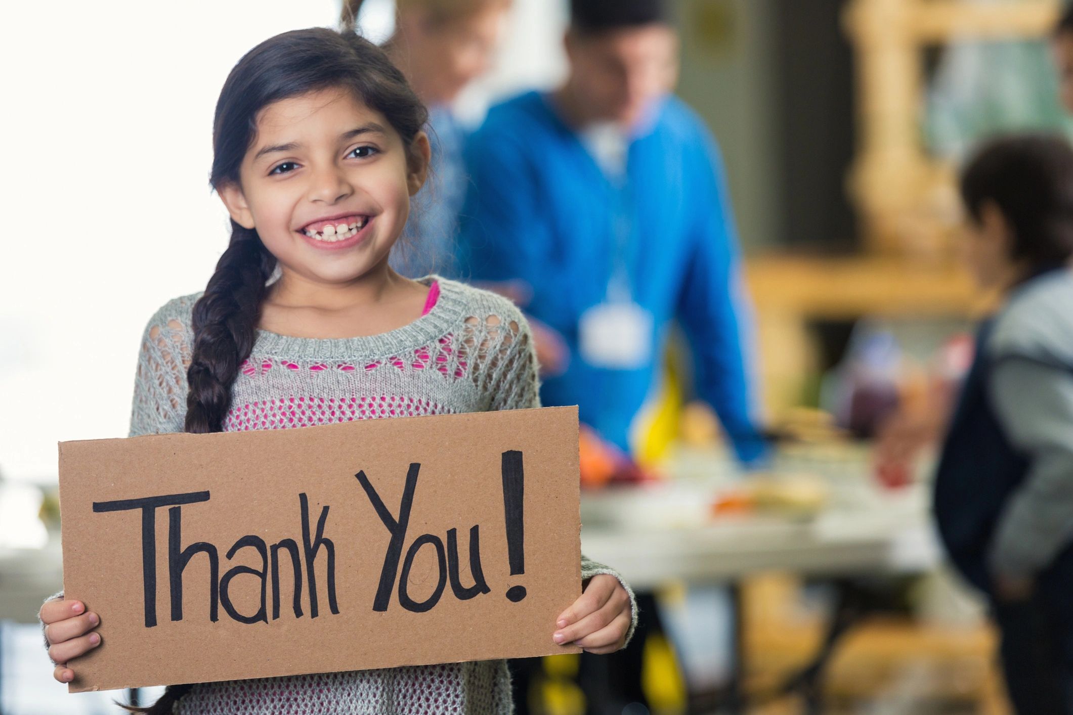 Child holding thank you sign at a charitable food outreach event
